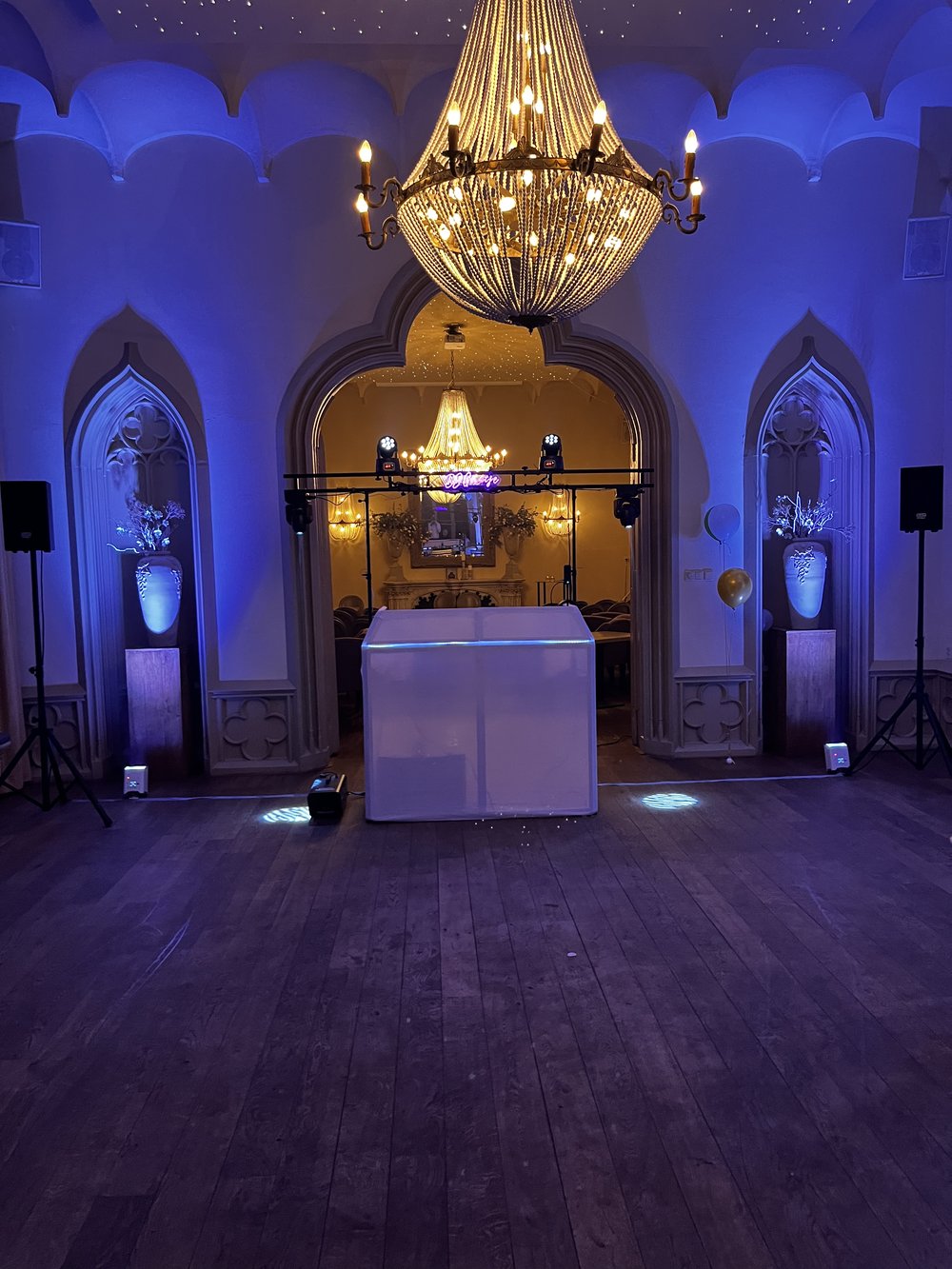 Bruiloft DJ-setup met blauwe uplights en kroonluchter